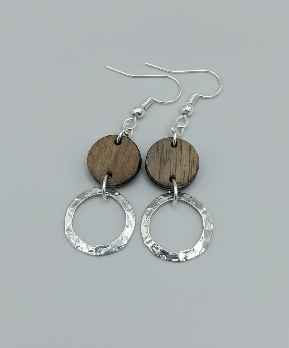 Wooden and silver hoop earrings on a wooden surface